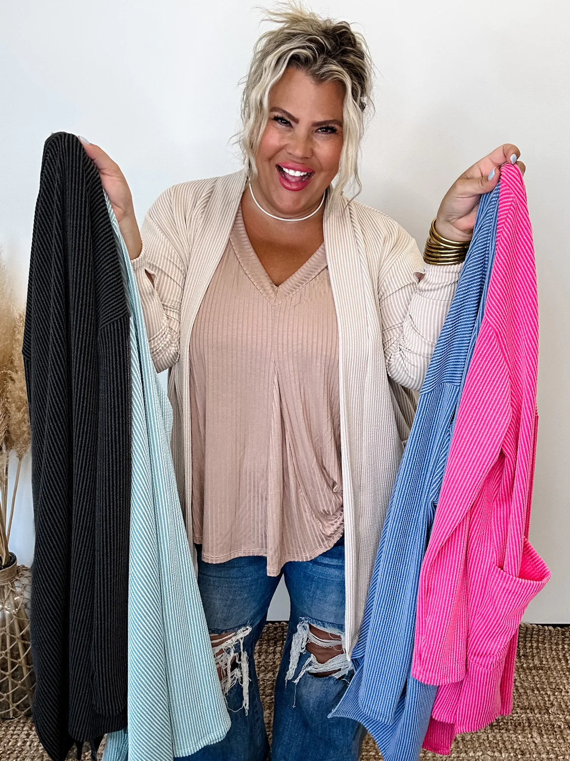 Blakeley holding up different color Cardigans. 